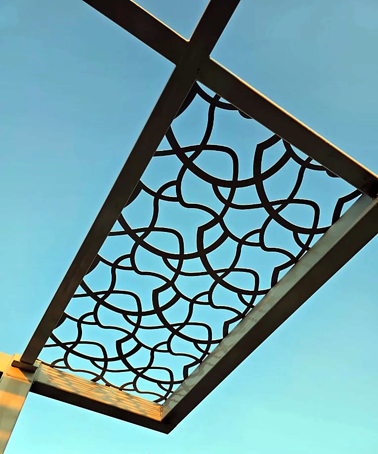 Laser-cut pergola infill panel with interlaced circle pattern against the sky