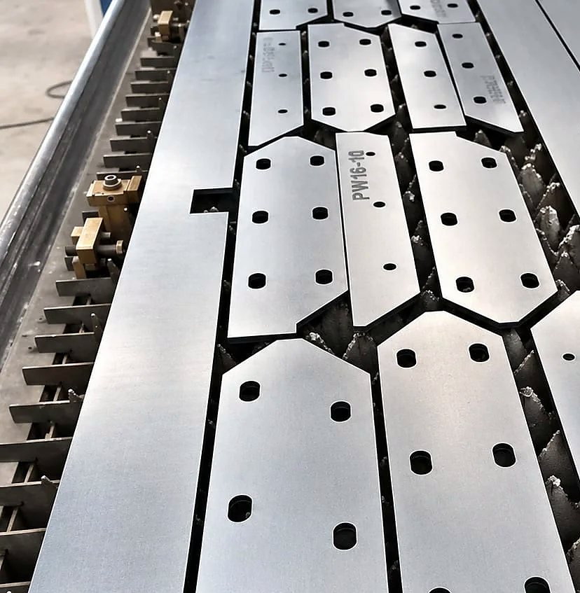 Nested laser-cut mild steel plates on the laser cutting bed in Ahmedabad